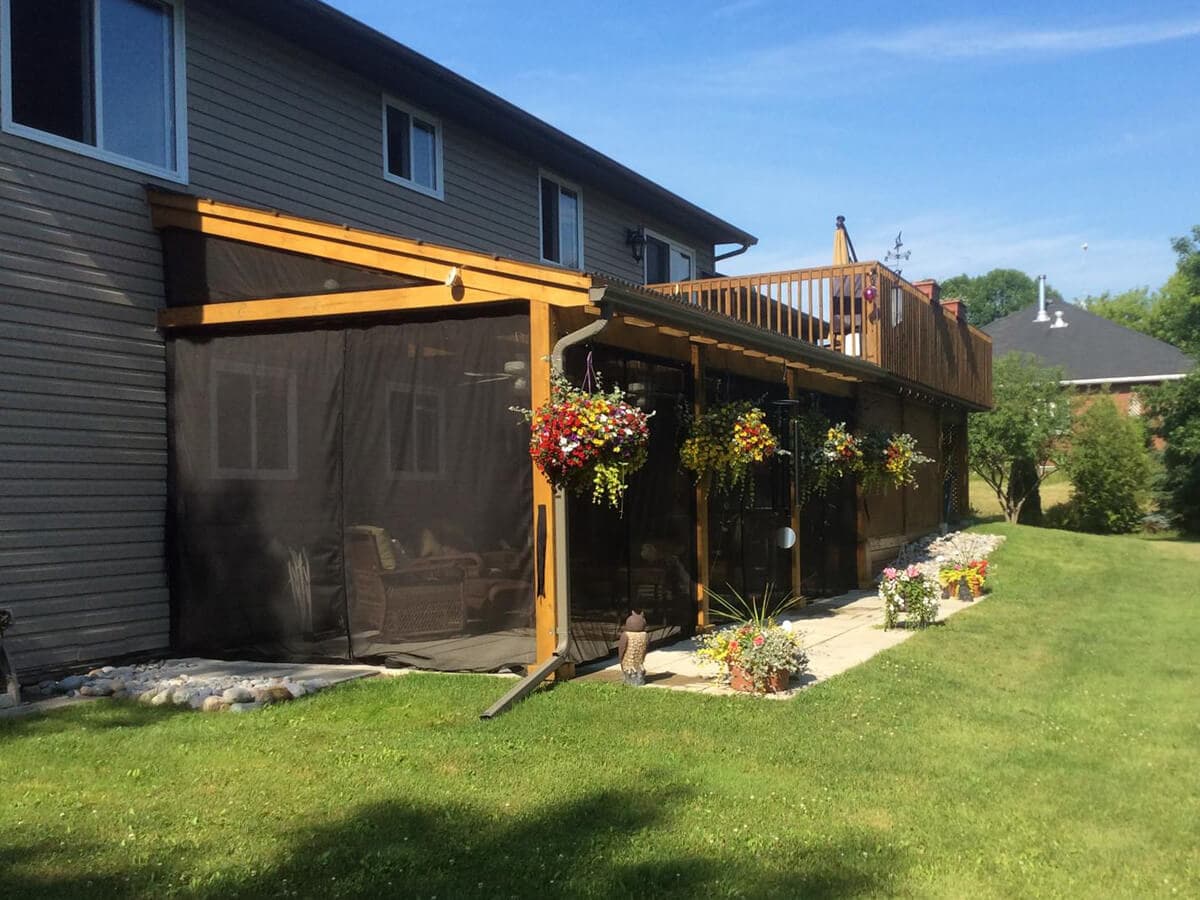 Under-deck patio enclosed with retractable mosquito screens on a cedar frame